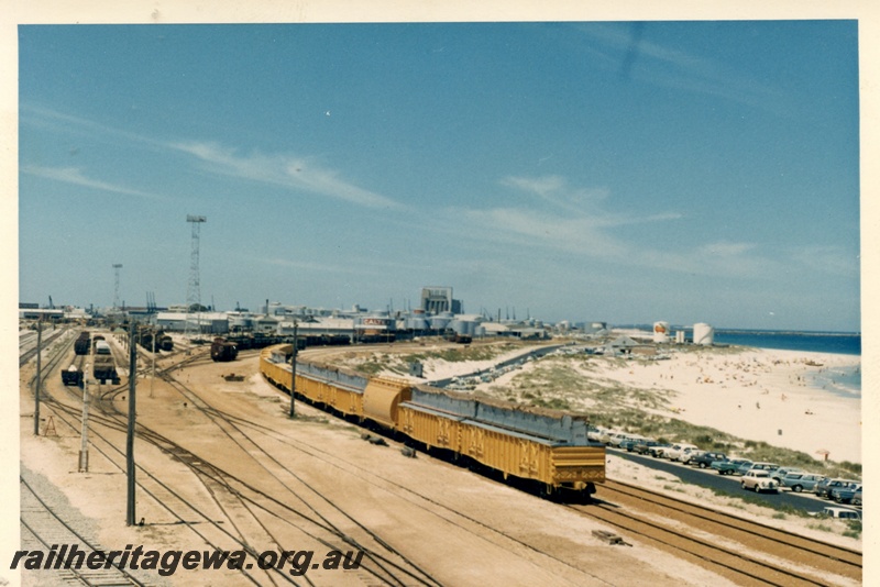 P17987
Rake of six WG class modified to convey wheat, the first two separated from the other four by a lone WW class grain hopper, elevated view of the yard looking south, being shunted to silos, Leighton yard, the port in background, ER line 
