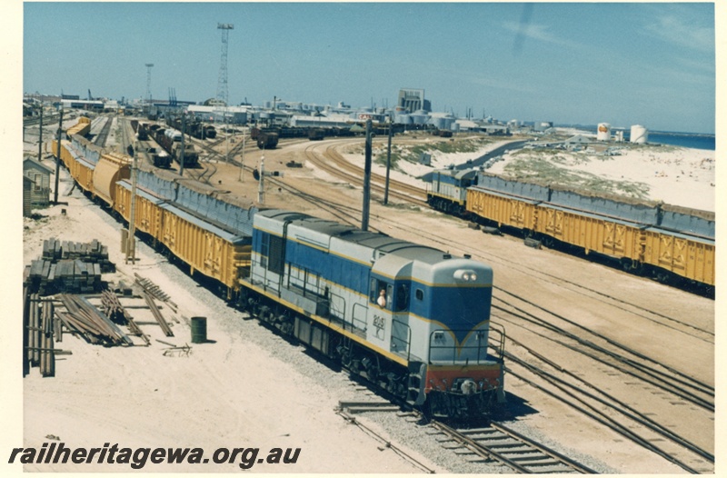 P17990
K class 205 on a grain train with WG class wagons modified to carry grain, J class shunting a rake of three WG class wagons modified to carry grain, elevated view of Leighton yard, beach, Fremantle port in background, ER line, c1966
