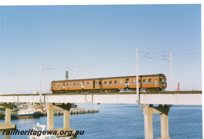 P18310
DMU set comprising ADG class railcar and ADA class railcar, crossing Fremantle bridge, side on view, new electric power poles already erected pending commencement of EMU operation
