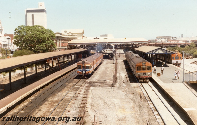 P18312
Three DMU sets, headed by ADA class railcar, ADB class 774 and ADK class railcar, front on view, platforms, canopies, horseshoe bridge, vacant area in foreground for overhead carpark construction, Perth city station, view from eastern end
