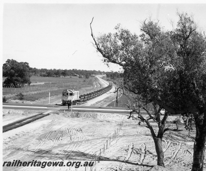 P18389
4 of 5 images of J class 101 on standard gauge ballast train comprising ex-Commonwealth Railways (CR) WSJ class hoppers near Kenwick, entering level crossing, Albany Highway, Kenwick
