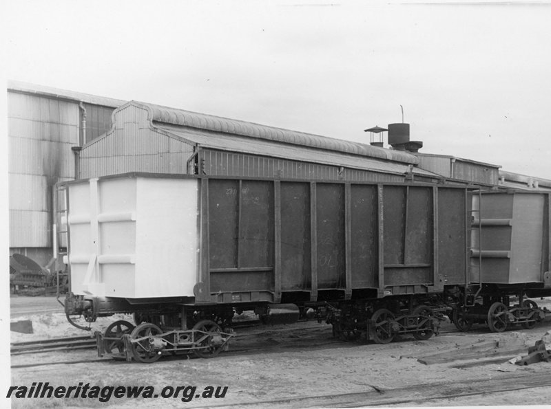 P18712
Two ore wagons on transfer bogies, in front of industrial building, end and side view
