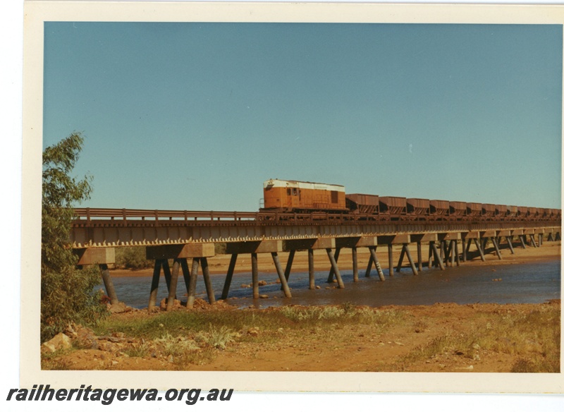 P18867
Goldsworthy Mining (GML) A class 4 hauls an empty ore train over the De Grey River road/rail bridge near Port Hedland. 

