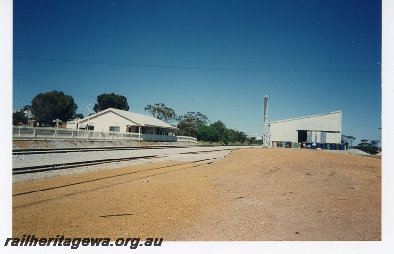 P18979
Station building, platform crane, goods shed, Goomalling, EM line, station building fenced off, view along the line looking east
