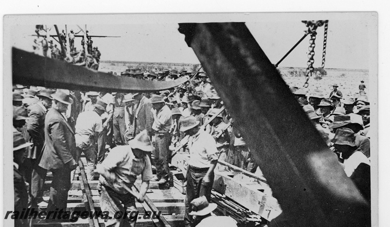 P19203
Commonwealth Railways (CR) worker John Reilly driving in the last dog spike to complete the Trans-Australian Railway, onlookers, TAR line
