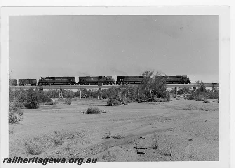 P19219
Mount Newman Mining (MNM) 4 C636 class locomotives haul a loaded iron ore train over the Turner River near Gillam. 
