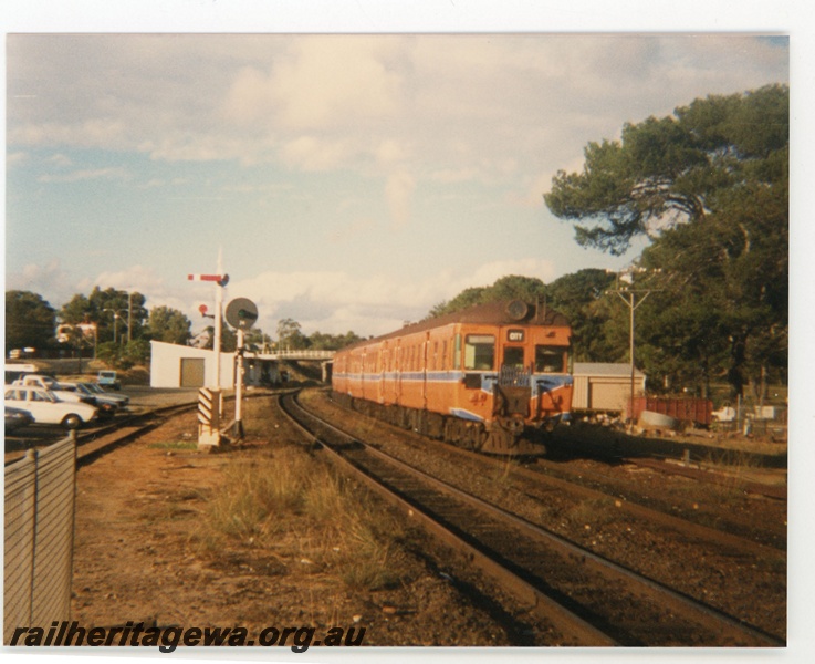 P19268
Suburban city bound DMU in orange livery with blue and white stripe, semaphore signal, light signal, road overpass, ER line, side and front view
