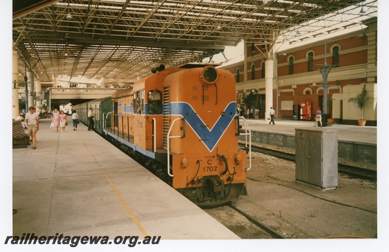 P19275
C class 1702 on passenger train, platform, pedestrian overpass, roof, main station building, travellers, Perth City station, side and end view from platform
