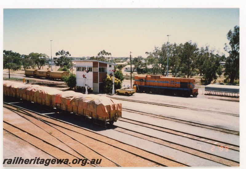 P19288
AA class 1519 in orange livery with blue and white stripe, rake of wheat wagons, rake of covered wagons, signal box, semaphore signals, yard, Narrogin, GSR line, elevated view
