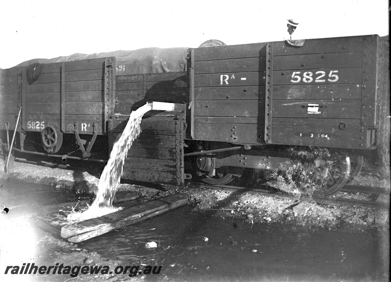 P19296
RA class 5825 five plank bogie open wagon, 400 gallon square iron water tank on board being emptied beside track, rail worker, c1904-1909
