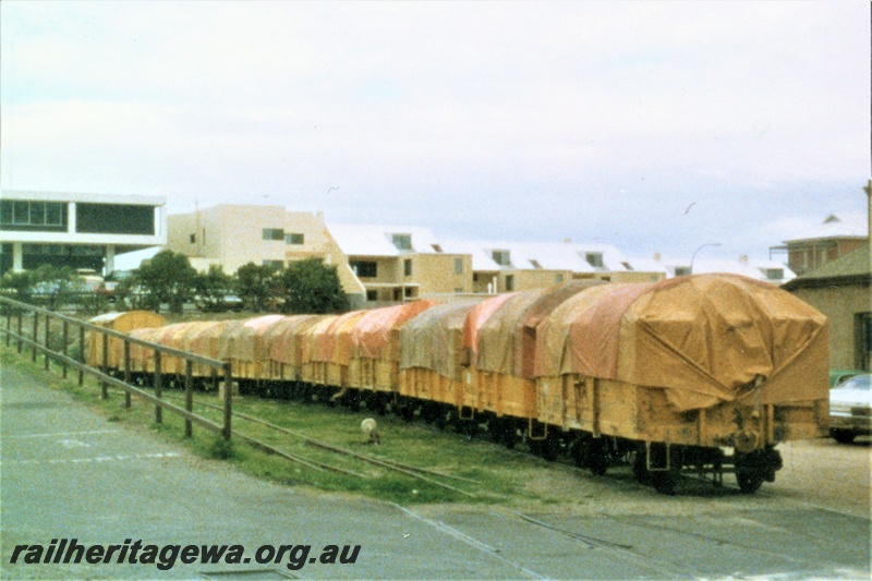 P19532
Rake of tarpaulin covered yellow livered four wheel wagons in the headshunt behind the 