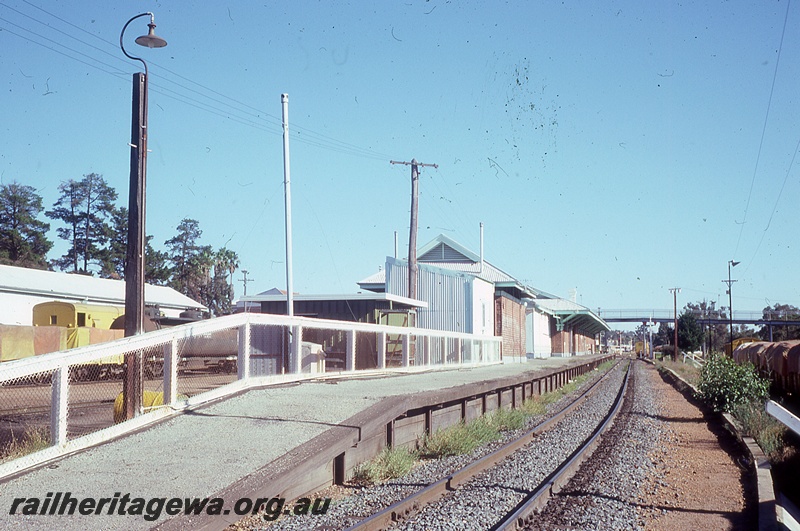 P19824
Station buildings, platform, goods shed, yard, wagons, track, pedestrian overpass, rake of covered wagons, Narrogin, GSR line
