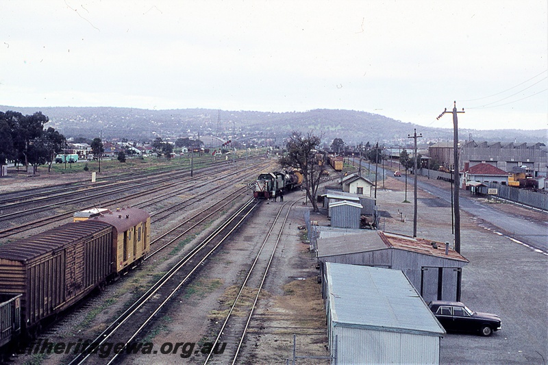 P19837
Yard, sidings, rake of goods wagons, diesel shunter, steam loco, vans, trackside and industrial buildings, Midland, ER line, view from elevated position to the east looking towards hills
