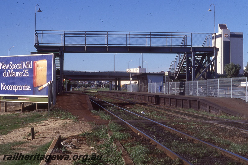P19856
Pedestrian footbridge, road overpass, billboard, platforms, tracks, West Perth, ER line, view from trackside
