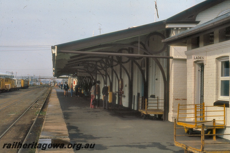 P19958
Station building, platform, luggage trolleys, onlookers, rake of goods wagons, signals, pedestrian overpass, Bunbury, SWR line
