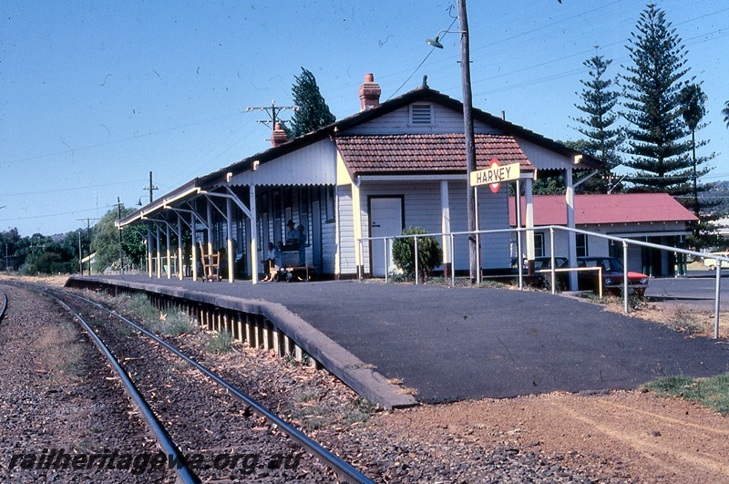 P19972
Station building, station nameboard, platform, passengers waiting, carpark, track, Harvey, SWR line
