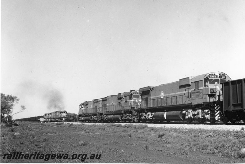P20491
Mount Newman Mining diesel locos 5469, 5454 and 5465 triple heading iron ore train, waiting on the main line, as another triple headed train of empties enters siding, Poonda, 80 km from Newman, trackside view
