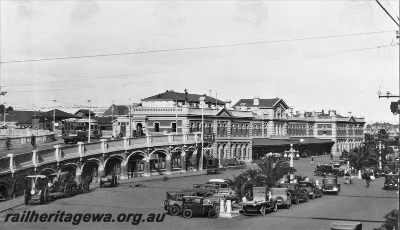 P21483
Perth Station, streetside view looking east from the Horsehoe Bridge, horse drawn vehicles and motor vehicles in the forecourt, tram on the Horsehoe Bridge
