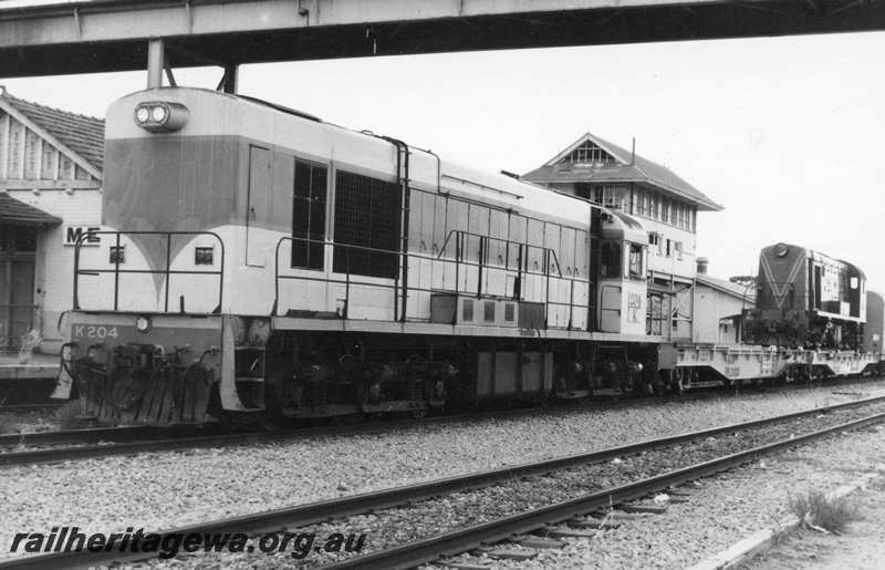 P21716
K class 204, on eastbound freight train, including flat wagon WFL class 30059 loaded with former MRWA F class 40, signal box, station building, platform, Merredin, EGR line, front and side view
