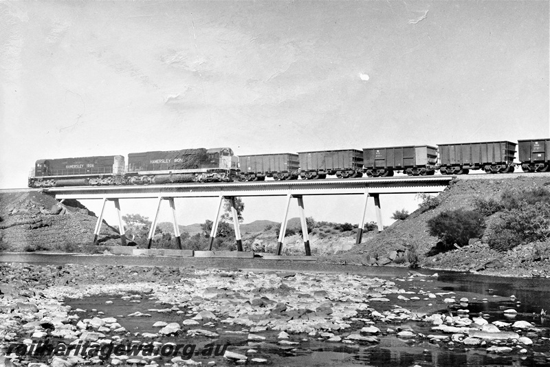 P22211
Hamersley Iron diesels numbered 2000 and 2005, double heading train of empties, crossing steel bridge over Harding River, Pilbara, side and rear view from river level
