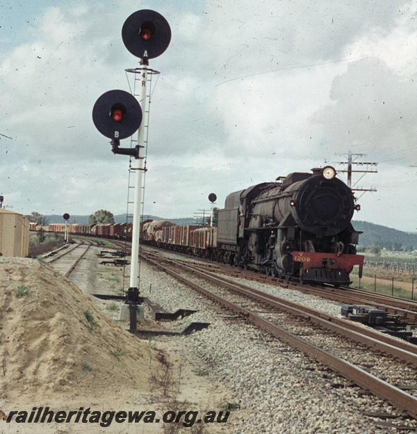 T04475
An unidentified V class steam locomotive heading No. 24 Goods through West Toodyay enroute to Midland. Note the coloured light signal at the left. Avon Valley line
