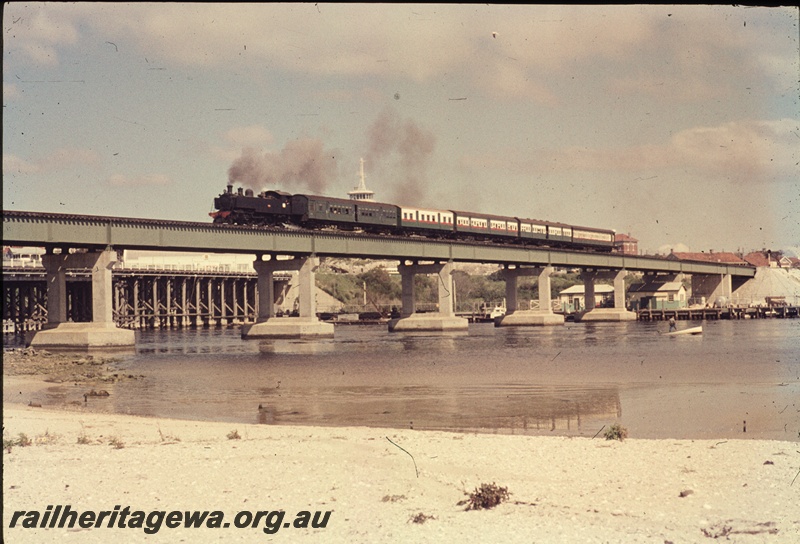 T04533
An unidentified DD/DM class steam locomotive with a suburban passenger set travelling over the Fremantle Bridge enroute to Perth.
