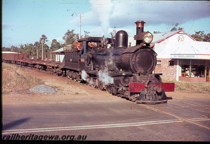 T04542
State Saw Mills loco SSM No.2 travelling across a level crossing with a rake of empty flat wagons and open wagons in the Manjimup area.
