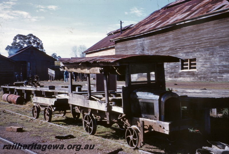T04877
Motor vehicle with corrugated iron roof, on rails, wooden wagon, wooden buildings, wooden platform, Millars Workshops, Yarloop, SWR line
