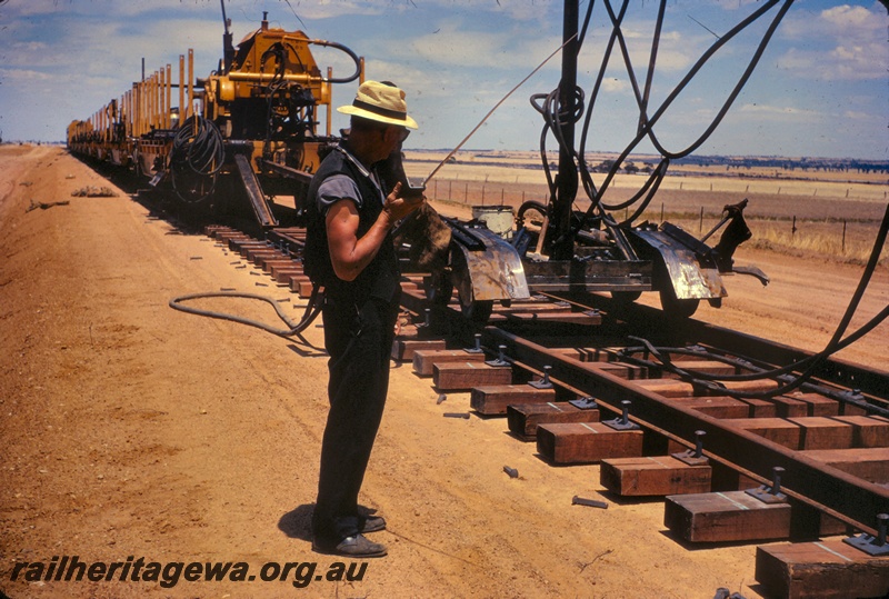 T05025
Track laying, machinery, train, guard Stan Williams, directing operations by walkie talkie radio, rural setting
