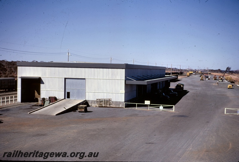 T05059
Freight terminal building, yard, vans, crane loading wagons at loading ramp, various motor vehicles, West Kalgoorlie, EGR line 
