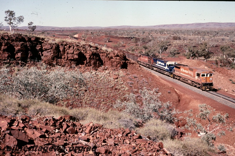 T05193
BHP Iron Ore (BHPIO) C39-8 class 5632 (Mount Newman orange livery), M636 class 5495 (BHPIO blue livery) lead a loaded iron ore train near Newman.
