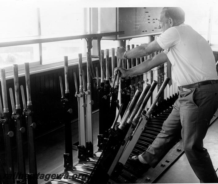 P00922
Signalman, signal levers, internal view of box showing signalman pulling a lever. Kwinana signal cox.
