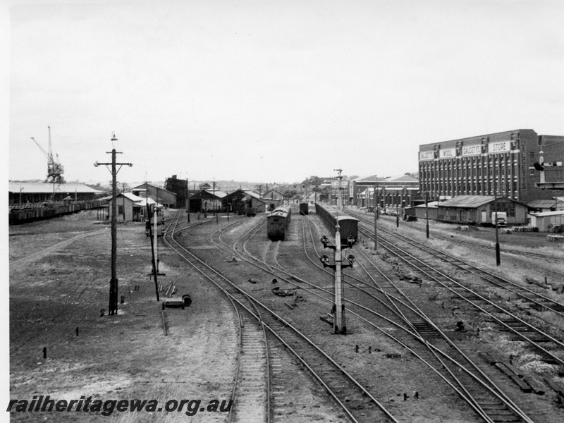 P01724
Fremantle yard, ER line, looking towards Perth, showing carriage sidings and loco depot, signals, points, Dalgety's wool stores, wharf crane.
