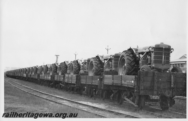 P01786
1 of 3 images of a rake of H class wagons loaded with Chamberlain tractors, side and end views
