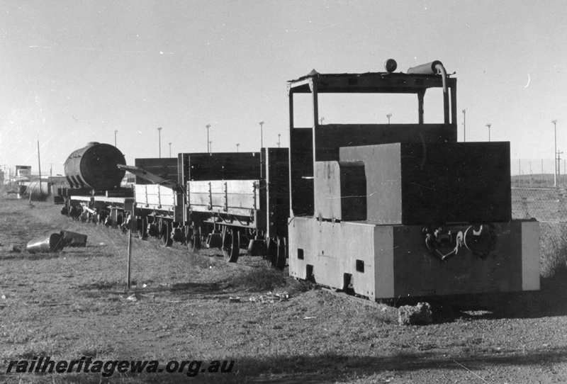 P01897
PWD jetty loco PW24 at the head of a line of four wheel wagons, Roebourne, side and front view, on display.
