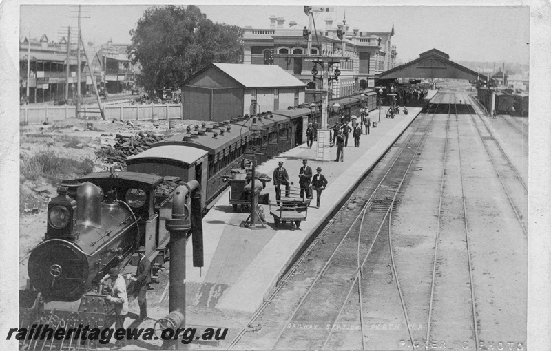 P01974
Perth Station, elevated overall view from the east end looking west, loco and passenger train in the dock platform, water column, bracket signal, oil lamps on the platform, overall roof in the background
