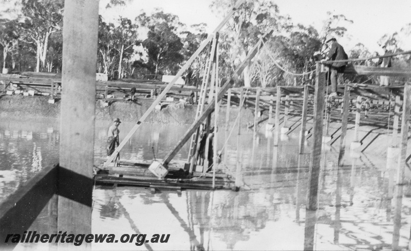 P02074
10 of 12 views of the construction of a railway dam at Hillman, BN line, view of raft pulling post up from horizontal position to a vertical one by means of triple and double blocks.
