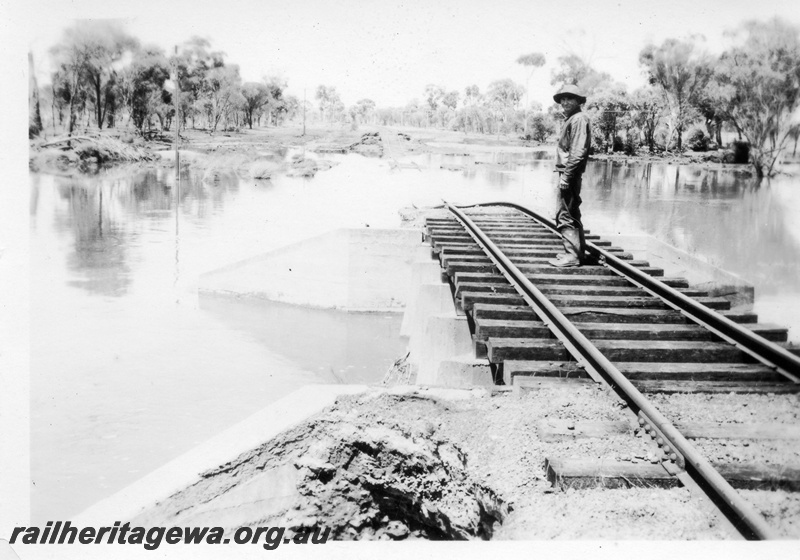 P02125
1 of 7 views of flooding and washaways on the Narrogin to Wagin section of the GSR, worker standing on a short culvert surrounded by flood waters and a section of track washed away
