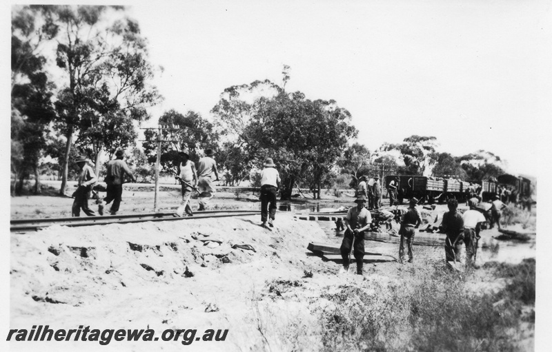 P02128
4 of 7 views of flooding and washaways on the Narrogin to Wagin section of the GSR, workers restoring a section of track washed away, wagons with ballast on the far side of the washed out culvert. 
