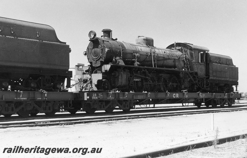 P02401
W class 934 steam locomotive loaded on Commonwealth Railways (CR) QB class 2406 flat top wagon on route to Pt Augusta, front and side view.
