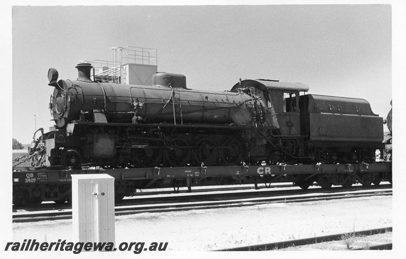 P02404
W class 934 steam locomotive loaded on Commonwealth Railways (CR) QB class 2407 flat top wagon on route to Pt Augusta, front and side view.
