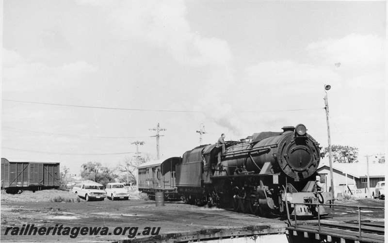 P02410
1 of 2. V class 1219 steam locomotive, side and front view, approaching turntable, louvered van and brakevan in the background, Bunbury, SWR.
