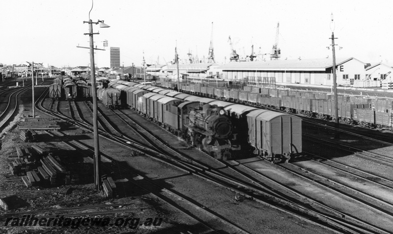 P02534
PMR class 724 steam locomotive, side and front view, Fremantle yard with lines full of rolling stock, E shed in the background, ER line. circa late 1960s.
