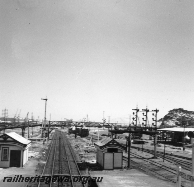 P02710
Elevated view of North Fremantle station from footbridge looking towards Fremantle, double tracks, sidings, gantry signals, nameboard, footbridge, buildings, ER line.
