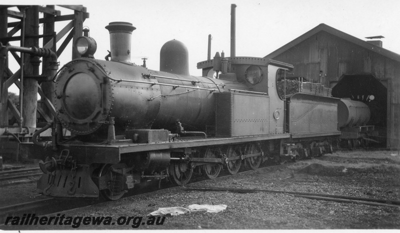 P02724
O class 98 steam locomotive, front and side view, outside loco shed, next to water tower, Busselton, BB line.
