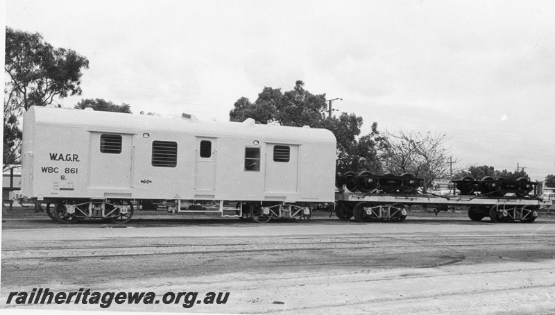 P02795
WBC class 861 standard gauge brakevan. Islington Works, South Australia, on transfer bogies, bogies on a flat wagon coupled to the brakevan, side view.
