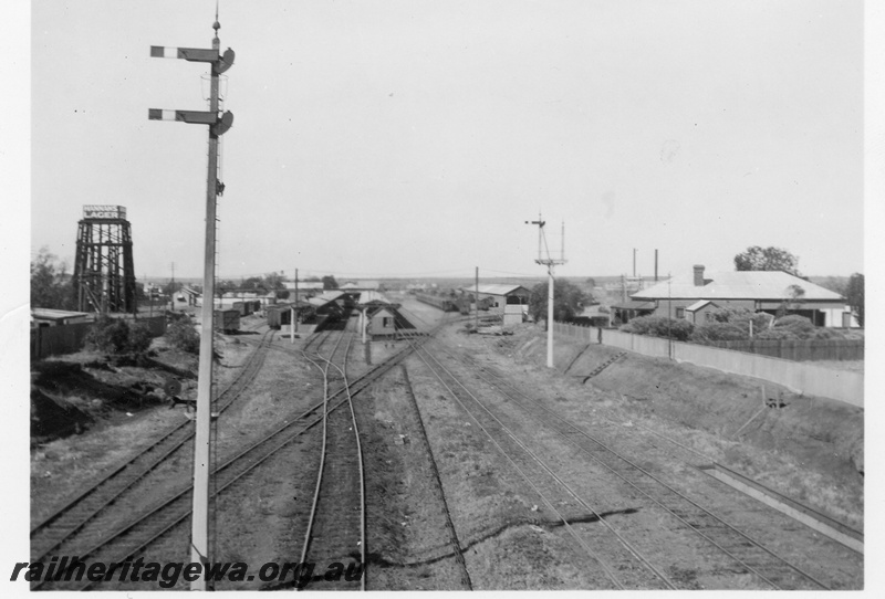 P02815
Kalgoorlie station view from eastern approach, water tower with 25,000 gallon cast iron tank with Hannan's Lager painted on the side, signals, platforms, sidings, standard gauge tracks in the centre.
