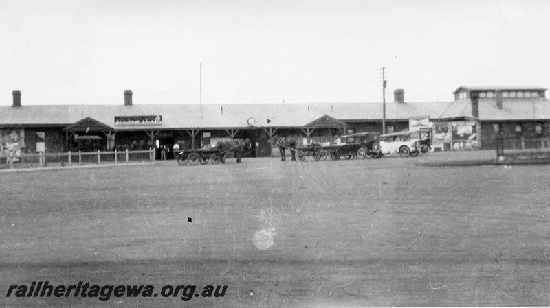 P02816
Kalgoorlie station forecourt, horses and carts, motor vehicles, station clock.
