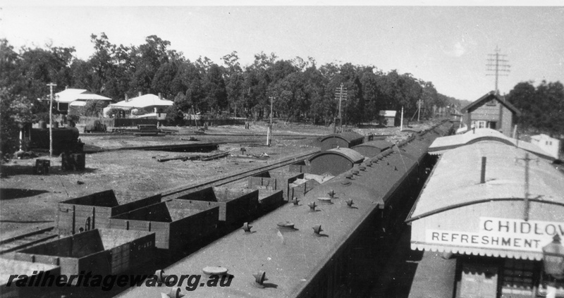 P02831
Station buildings including the refreshment room and signal box, SM's house, turntable, open wagons, loco approaching the turntable, passenger train at the passenger platform, elevated view, looking west, Chidlow, ER line.
