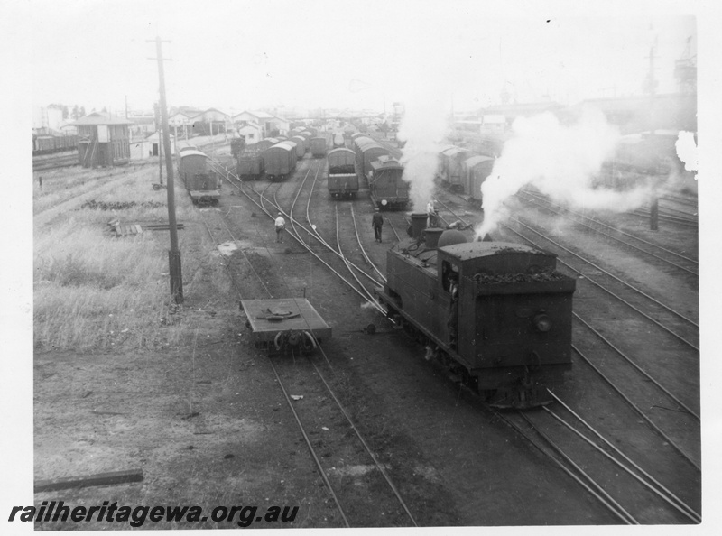 P02843
K class 105 steam locomotive, side and end view, shunting, signal box, passenger platforms in the background, wagons on the sidings, Fremantle, ER line. 
